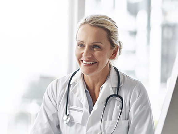 Kvinnelig allmennlege som smiler til pasient.