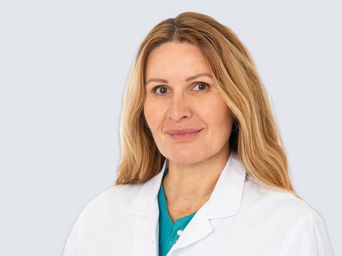 Portrettbilde av en smilende, kvinnelig kirurg.