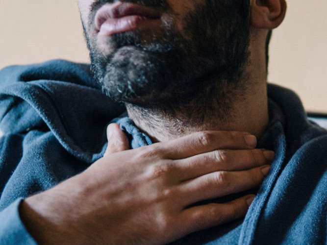 mann tar seg til halsen. foto.