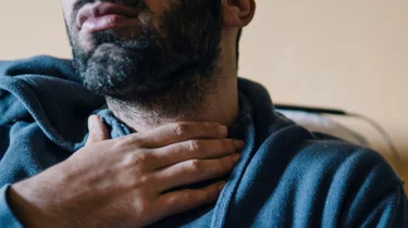 mann tar seg til halsen. foto.