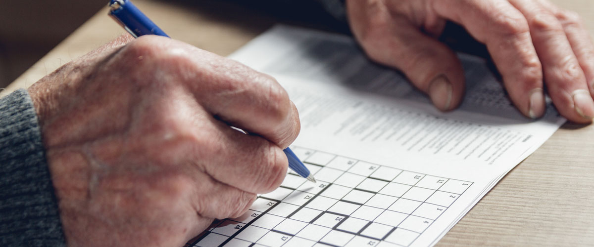 Eldre mann som løser kryssord.