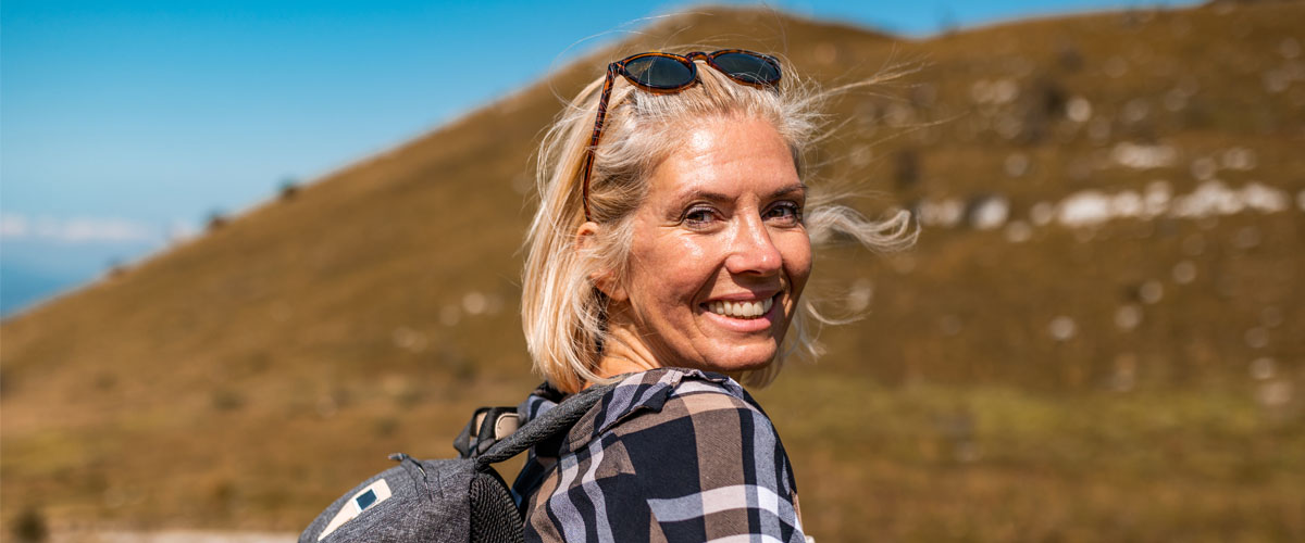 Dame på tur i fjellet som smiler mot kamera.