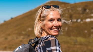 Dame på tur i fjellet som smiler mot kamera.