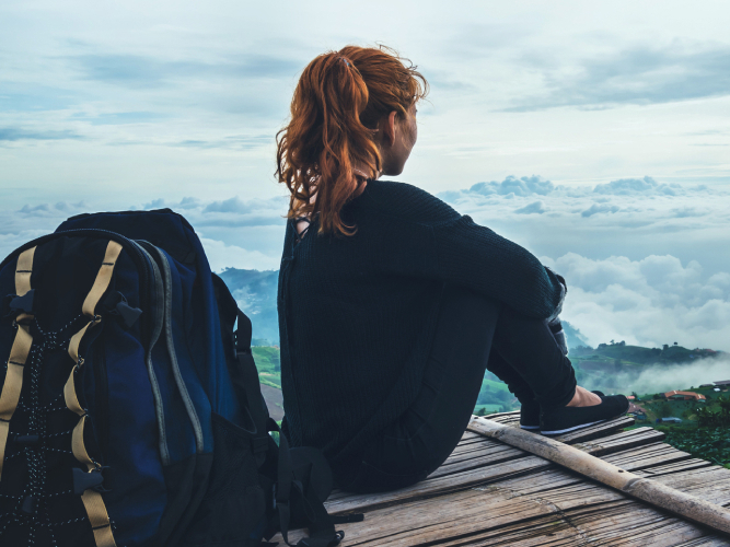 Kvinne på tur i skogen som sitter og nyter utsikten.