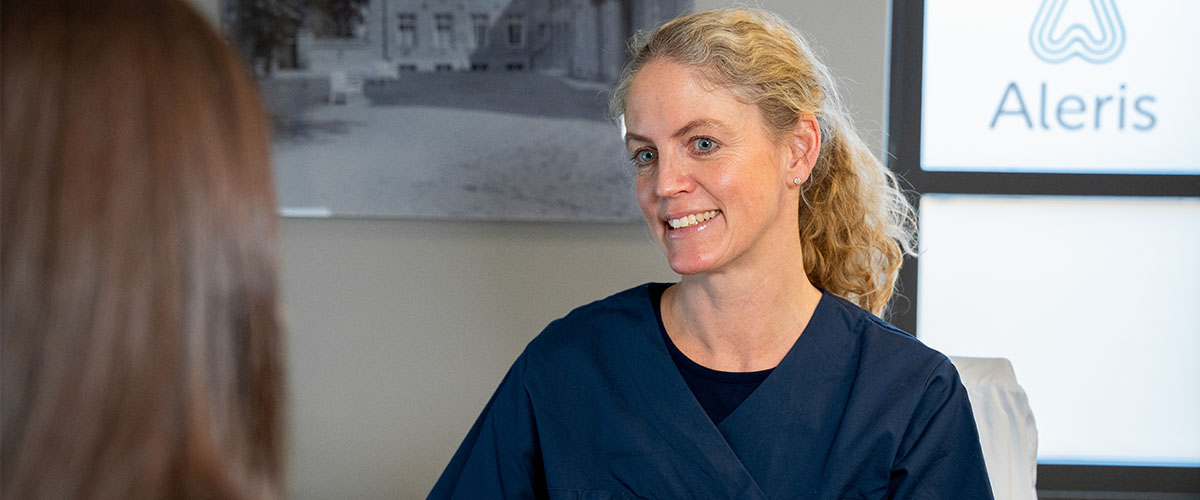 Gynekolog Tone R. Hafsteen i konsultasjon med mørkhåret kvinne. 