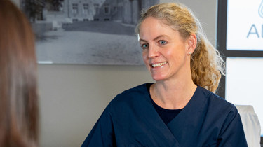 Gynekolog Tone R. Hafsteen i konsultasjon med mørkhåret kvinne.