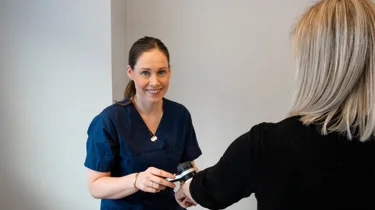 Hudlege Silje Davik undersøker en kvinnelig pasients hånd.