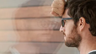 bekymret mann lener seg mot vindu.