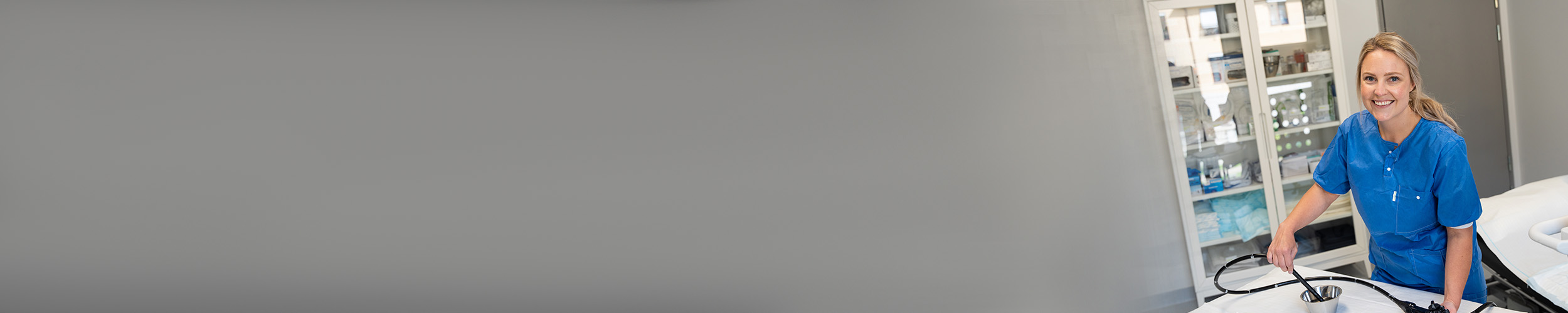 Kvinne som smiler og holder et skop inne på et behandlinsrom.