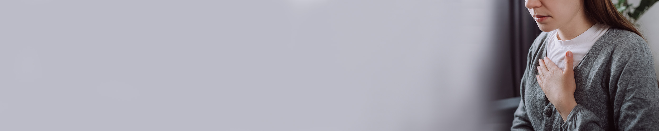 Nærbilde av kvinne som holder seg til brystet.