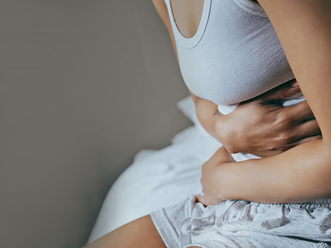 Nærbilde av en kvinne som holder seg til magen.