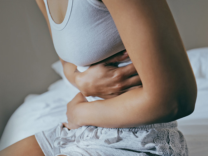 Nærbilde av en kvinne som holder seg til magen.