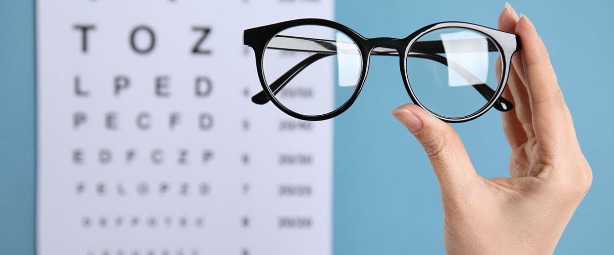 briller med synstest-kart i bakgrunnen. 