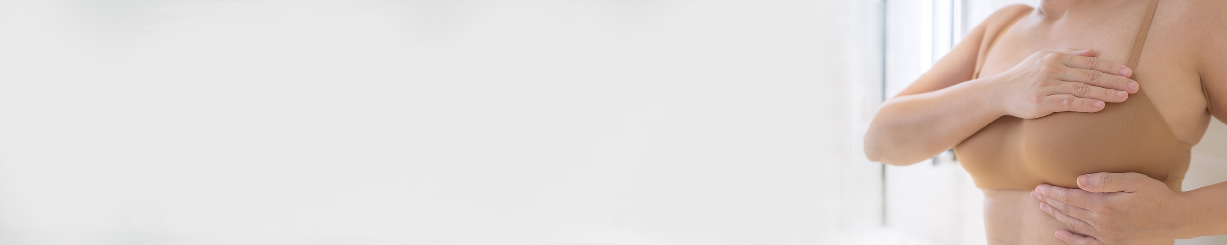 Kvinne holder hendene rundt det ene brystet