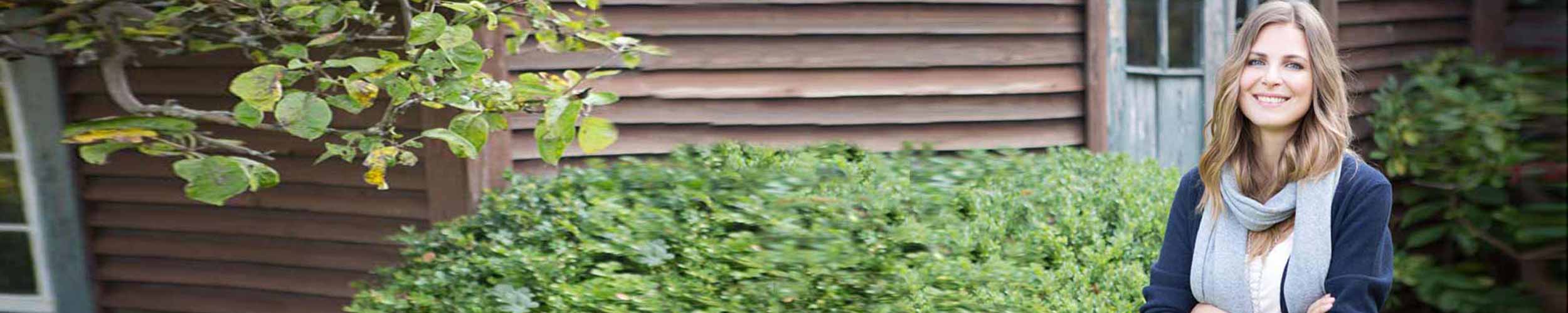 Kvinne står i grønn hage