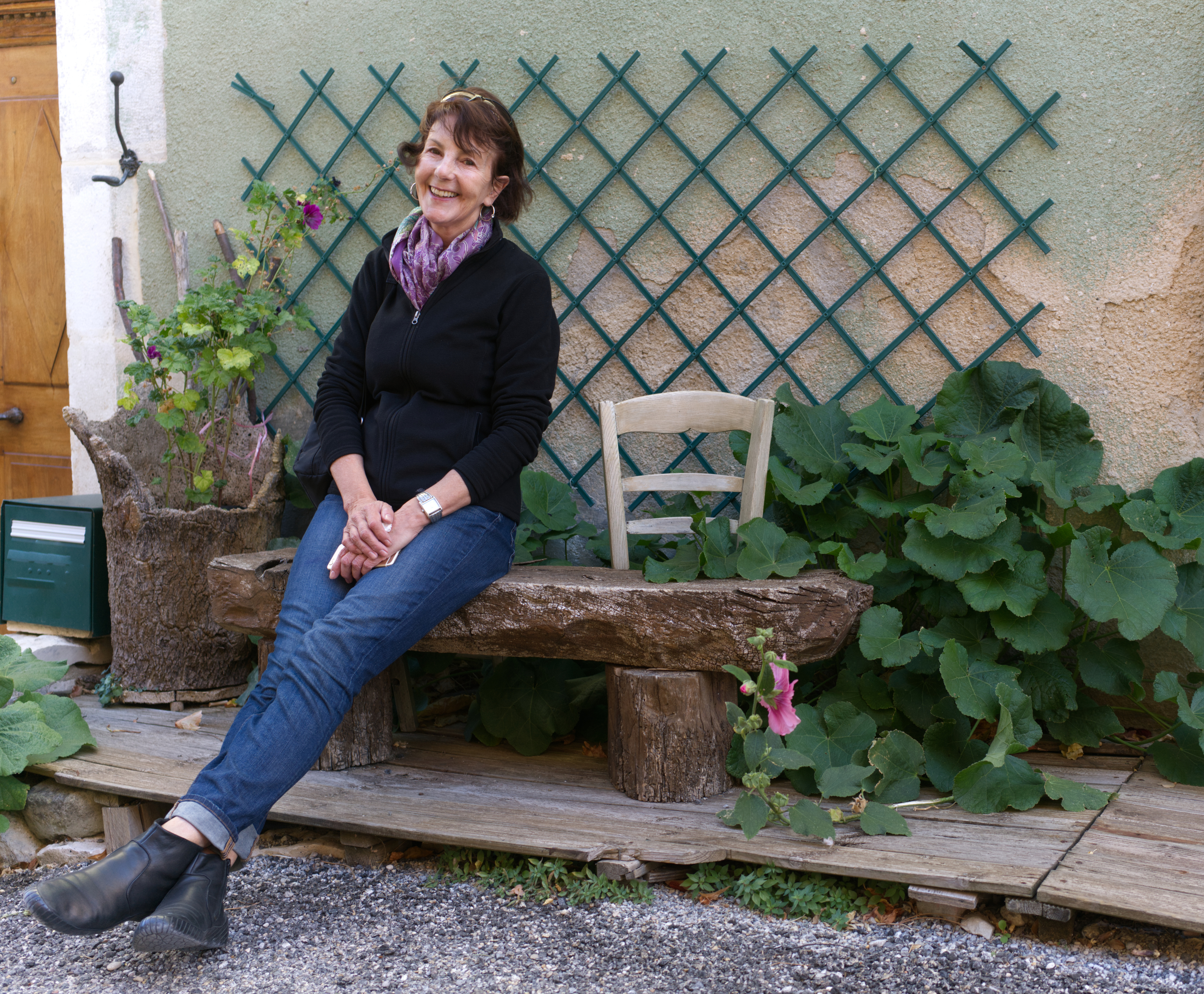 Kvinne sitter utenfor huset sitt med grønne planter