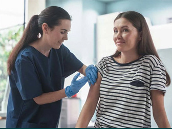 Kvinne får vaksine av lege