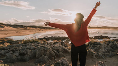 kvinne på utsiktspunkt med henda i været.