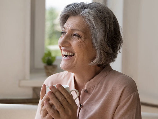 fornøyd dame 60 år sitter i sofaen.