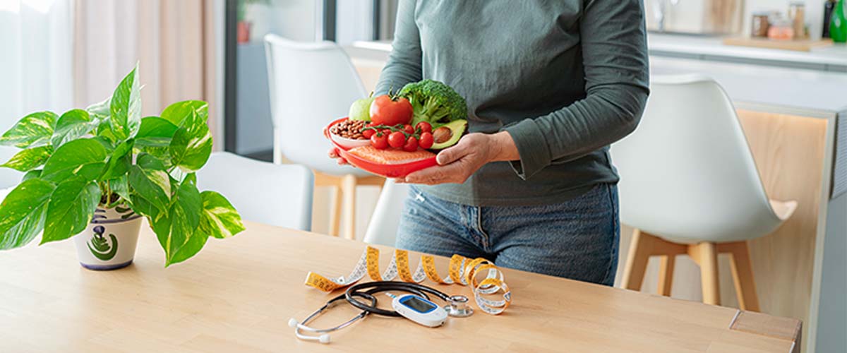 kvinne som lager sunn mat på kjøkkenet. målebånd og blodsukkermåler på bordet. 