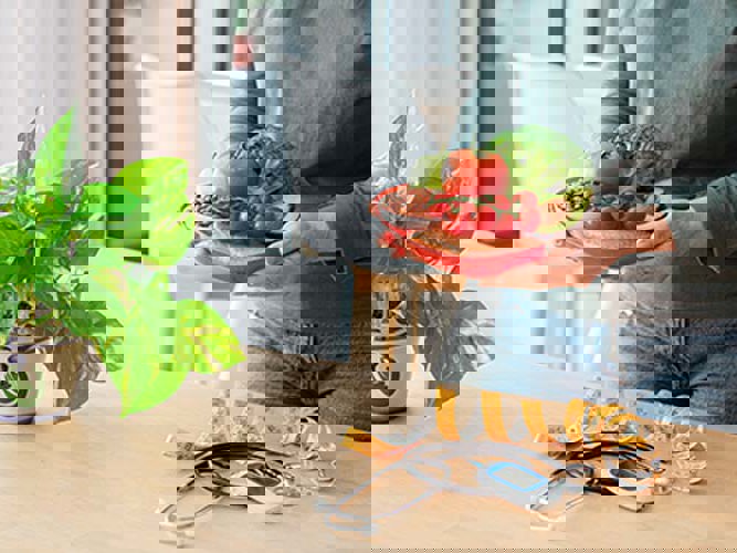 kvinne som lager sunn mat på kjøkkenet. målebånd og blodsukkermåler på bordet.