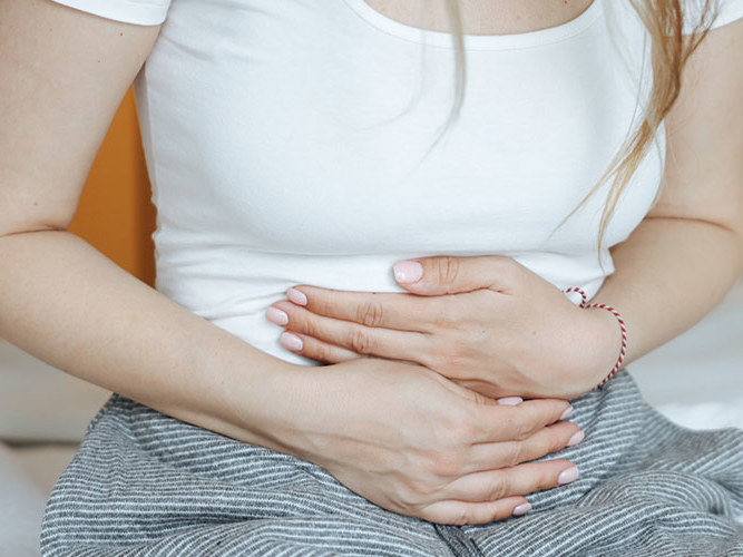kvinne som holder seg til magen.