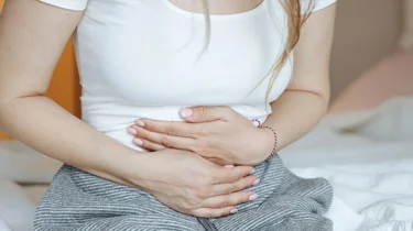 kvinne som holder seg til magen.