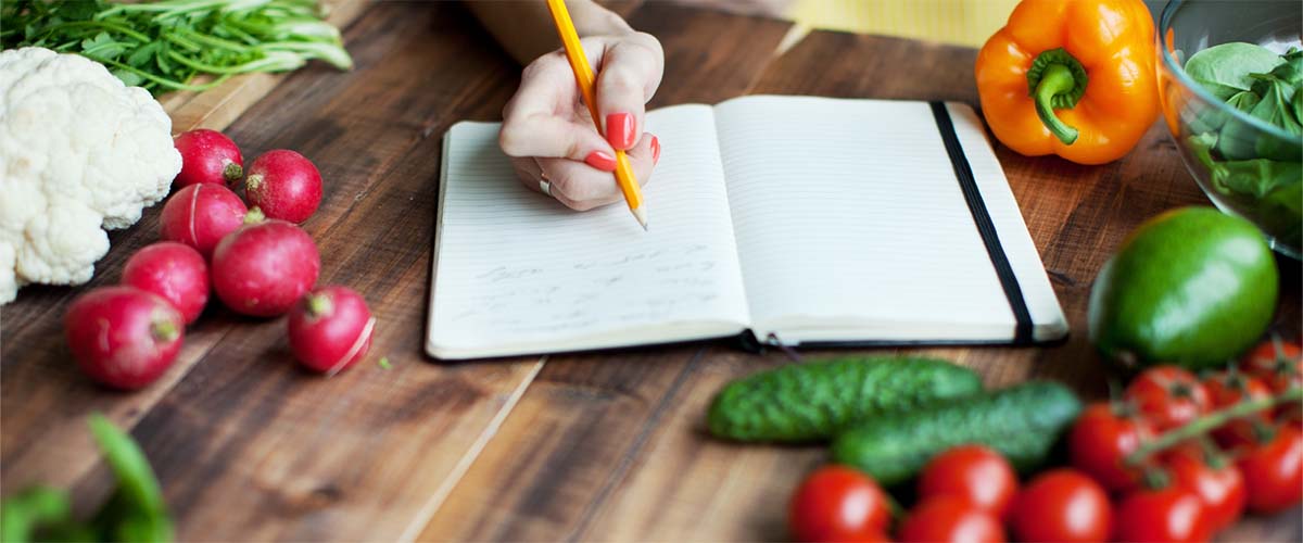 fargerik mat og en notatbok på en kjøkkenbenk. 