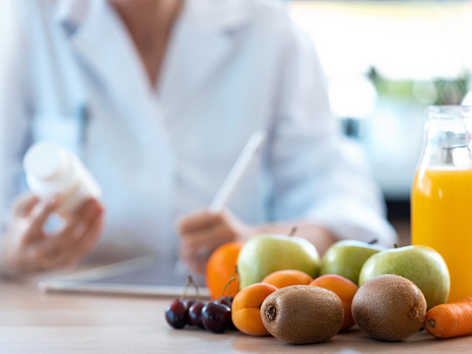 kvinne med en tablettboks i hånden. sunn mat i forgrunnen.