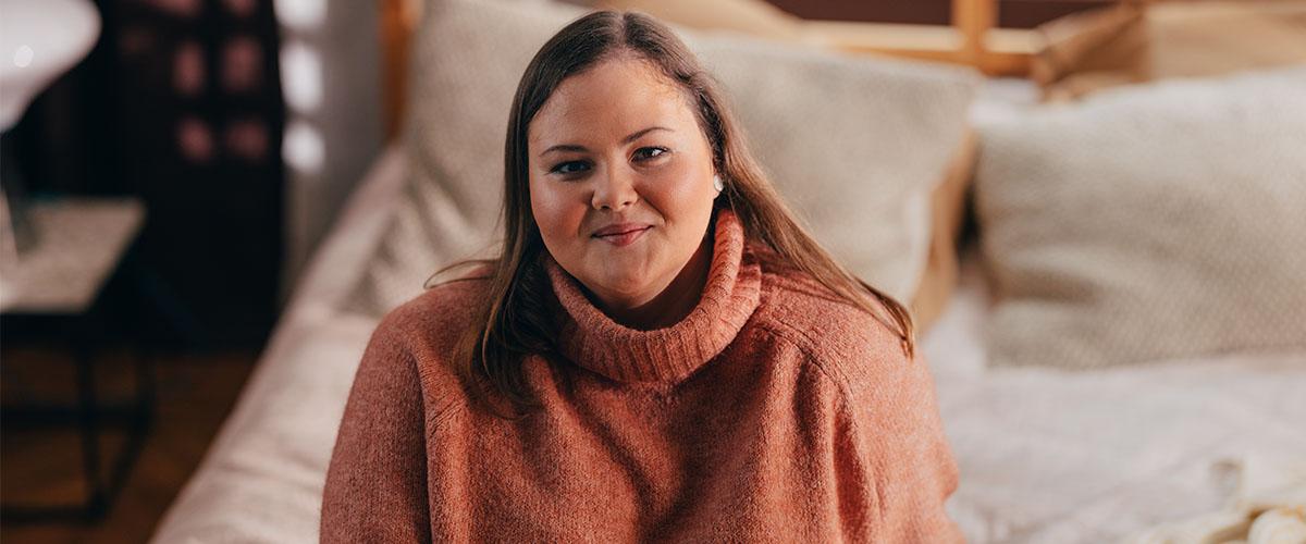 overvektig glad kvinne som sitter på sengen. 